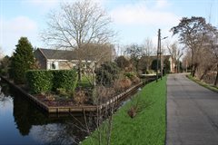 Impressiefoto ter hoogte van Bonrepas 24 na het afronden van de werkzaamheden. Het binnentalud is breder geworden en de palen van het stabiliteitscherm zijn gelijk met het waterpeil