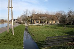 Impressiefoto ter hoogte van Bonrepas 7a na het afronden van de werkzaamheden. Het binnentalud is breder geworden en de palen van het stabiliteitscherm zijn gelijk met het waterpeil