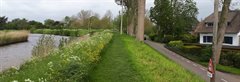 Regionale waterkering tussen Hekendorp en Oudewater. Aan de linkerkant loopt de watergang, aan de rechterkant staat een wit huis met een rieten dak naast de weg.