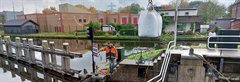 Man hijst zandzakken op een boot bij de Waaiersluis