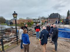 Bert de Groot geeft naast de loopbrug een uitleg bij de sluis