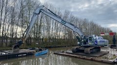 Kraan op een ponton heeft schepbak op een boot gelegd.