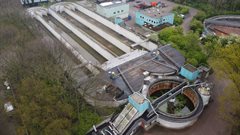 Een dronefoto van de rioolwaterzuiveringsinstallatie Maarssenbroek. De zuivering ziet er verouderd uit en verschillende onderdelen zijn bedekt met mos.