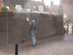 Medewerker spuit de Beermuur schoon ter plaatse van de coupure