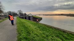 Medewerkers van Hoogheemraadschap de Stichtse Rijnlanden voeren een dijkinspectie uit en lopen over de dijk met oranje hesjes aan