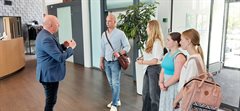 ontvangst op waterschapskantoor door hoogheemraad willem van der steeg in de hal van het waterschapskantoor. leerlingen Gwen, Amber en Milou met hun docent meneer Postma komen langs in Houten