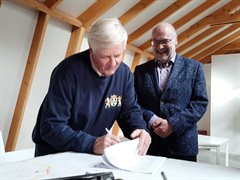 Ruud Mees, voorzitter van de Stichting Watererfgoed Groot Woerden, zet zijn handtekening en hoogheemraad Bernard de Jong kijkt glimlachend toe